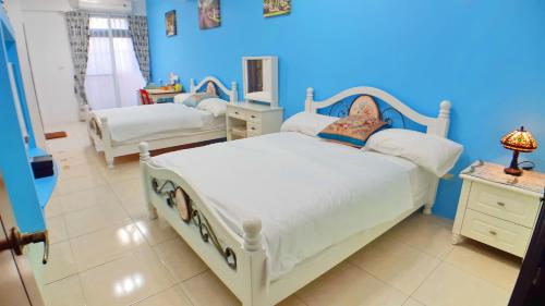 a bedroom with two beds and a blue wall at Loyofun in Donggang