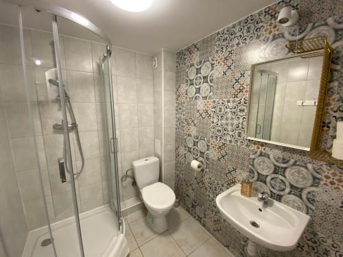 a bathroom with a shower toilet and a sink at Pastel Guest Rooms in Warsaw