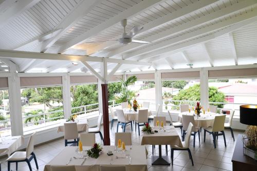 a restaurant with white tables and chairs and windows at Hôtel Saint-Georges in Saint-Claude