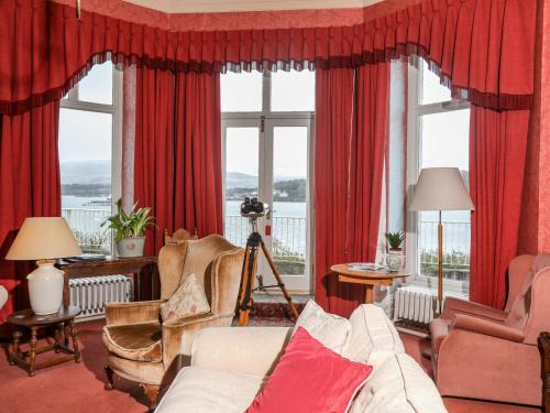 a living room with red curtains and a large window at Tan Y Coed in Menai Bridge