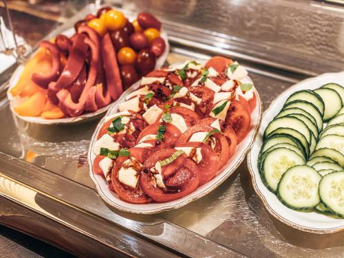 two plates of food on a glass counter with different foods at Hotel Schwertfirm in Karlsfeld