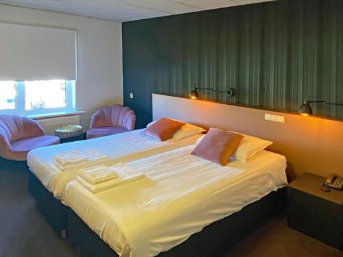 1 dormitorio con 1 cama grande y 2 sillas rosas en Dallinga, en Sluiskil