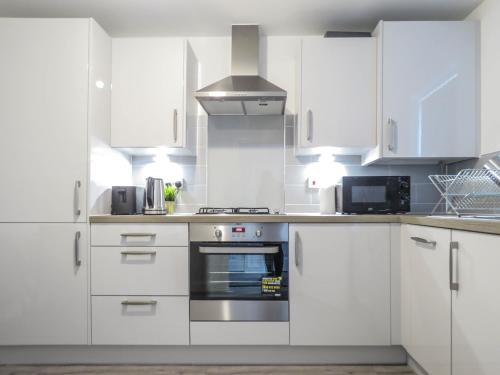 a kitchen with white cabinets and a stove top oven at Tudors eSuites 7 Single Beds Driveway & Garden in Birmingham