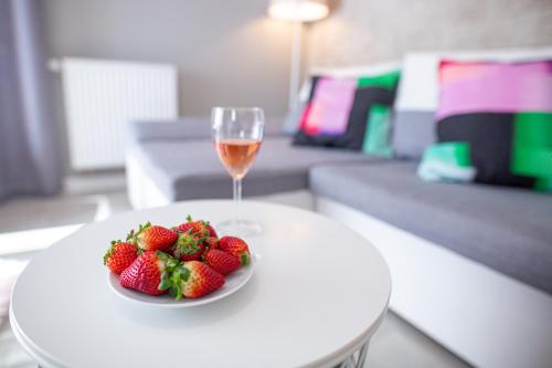 a plate of strawberries and a glass of wine on a table at Nadmorski Szept in Dziwnówek