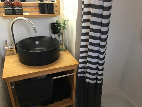 - un lavabo noir sur une table en bois avec rideau de douche dans l'établissement Saint-Pierre-la-Mer, à Fleury