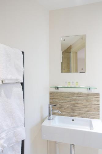 a white bathroom with a sink and a mirror at Railway Apartments in Nailsworth