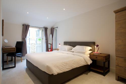 a bedroom with a bed and a desk and a window at Railway Apartments in Nailsworth