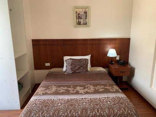a small bedroom with a bed with a wooden headboard at Rio Hotel in Riobamba