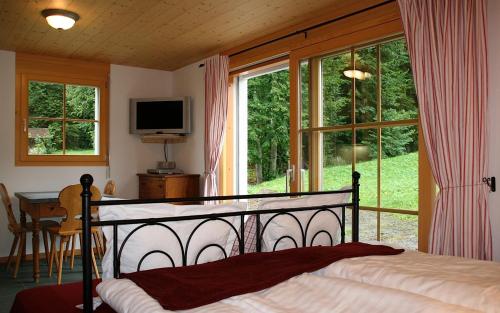 Schlafzimmer mit einem Bett, einem Tisch und Fenstern in der Unterkunft Sam & Cindy Mühlemann in Interlaken