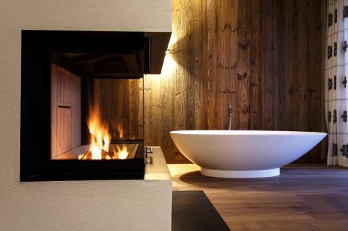
a white bath tub sitting in front of a fireplace at Sporthotel Ellmau in Tirol in Ellmau
