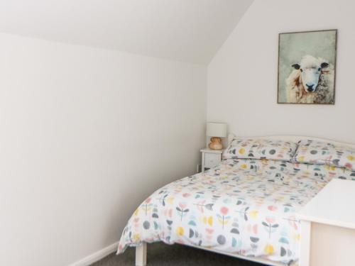 um quarto com uma cama com uma imagem de ovelha na parede em Tricker's Cottage em Attlebridge