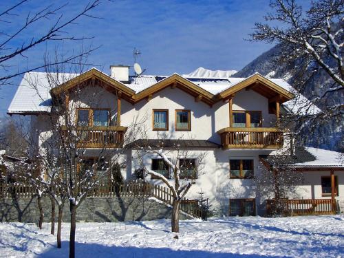 une maison enneigée avec un balcon dans la neige dans l'établissement Appart Gfall, à Ried im Oberinntal