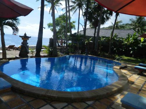 a large blue swimming pool next to the beach at Bali Bhuana Beach Cottages in Amed