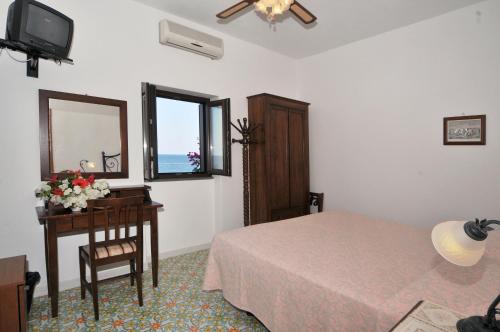 um quarto com uma cama, uma mesa e um espelho em Hotel Villaggio Stromboli - isola di Stromboli em Stromboli