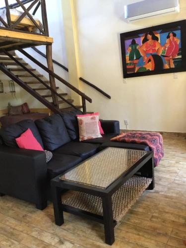 a living room with a black couch and a staircase at Cabañas de Bella Vista in Bella Vista