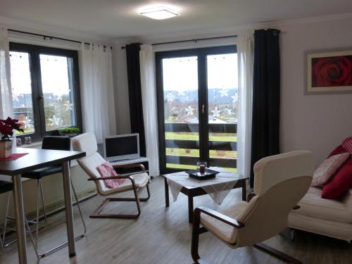 a living room with a table and chairs and windows at L'Horizon Studios & Apparts in Malmedy