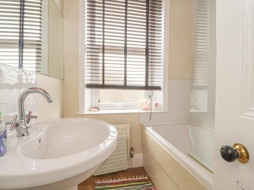 a white bathroom with a tub and a sink at Craven House in Skipton