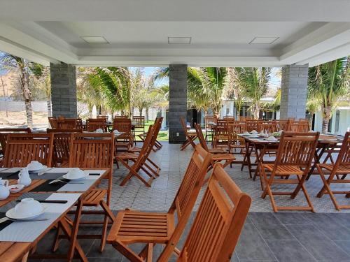 un ristorante con tavoli e sedie in legno e palme di Starlight Villa Beach Resort & Spa a Phan Thiet