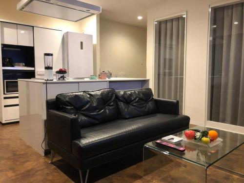 a living room with a black leather couch and a table at HOTEL xcell in Fukuyama