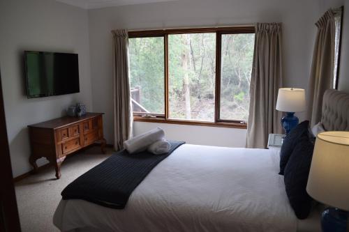 una camera da letto con un letto e una grande finestra di Bluebell Cottage a Leura