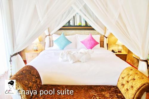 a bedroom with a large white bed with colorful pillows at The Chaya Resort and Spa in Chiang Mai