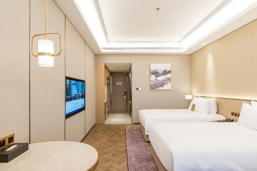 a hotel room with two beds and a flat screen tv at Mercure Changzhou Jintan in Changzhou