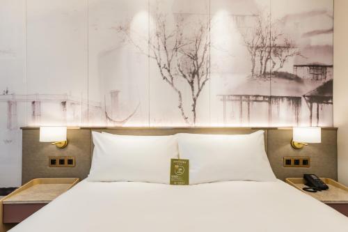 a bedroom with a white bed with a poster on the wall at Mercure Changzhou Jintan in Changzhou