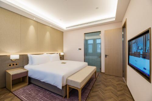 a bedroom with a large bed and a flat screen tv at Mercure Changzhou Jintan in Changzhou