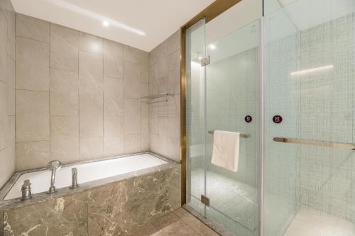 a bathroom with a tub and a glass shower at Mercure Changzhou Jintan in Changzhou