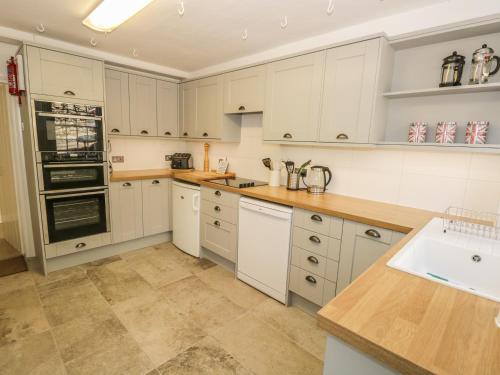 a kitchen with white cabinets and a sink at Town End Farmhouse in Newby Bridge