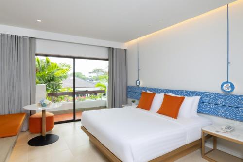 a bedroom with a white bed and a large window at Novotel Rayong Rim Pae Resort in Klaeng