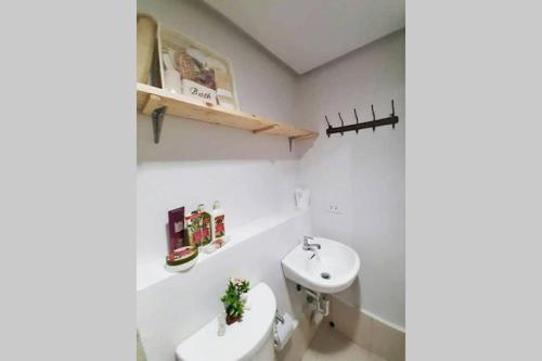 een witte badkamer met een wastafel en een toilet bij Pine Suites Tagaytay by StayPlus PH (Black and White Suite) FREE PARKING, CABLE TV, and WIFI in Tagaytay