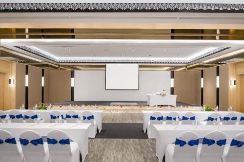 a banquet hall with white tables and blue chairs at Novotel Rayong Rim Pae Resort in Klaeng