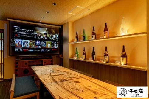 a dining room with a wooden table and a tv at KONJAKUSO Osaka Shinsaibashi "TARUKAISEN" Rooftop SPA in Osaka