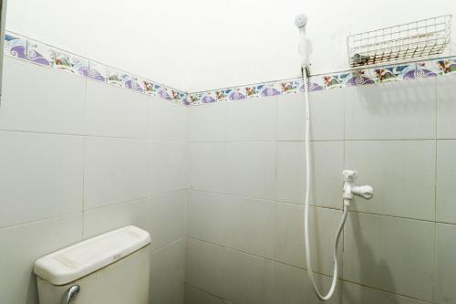 a white bathroom with a shower with a toilet at Kos VIP Josh in Yogyakarta