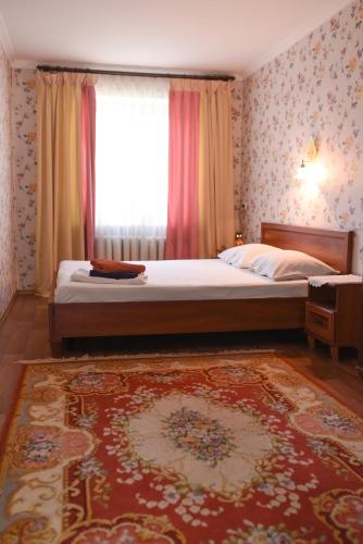 a bedroom with a bed and a window and a rug at Apartment Chernovola 7A in Shostka