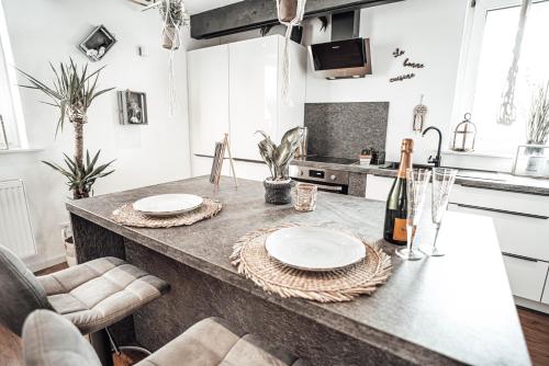 a kitchen with a counter with two plates and a bottle of wine at Luxusloft Timeout with private Spa in Ralingen