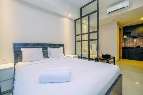 a bedroom with a large white bed in a room at Warm and Cozy Studio at The Oasis Cikarang Apartment By Travelio in Cikarang