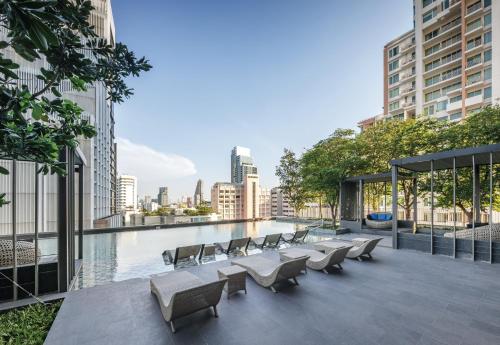 un patio all'ultimo piano con sedie e una piscina in un edificio di Oakwood Suites Bangkok a Bangkok