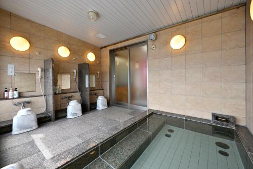 a bathroom with a tub and two toilets in it at Saijo Urban Hotel in Saijo