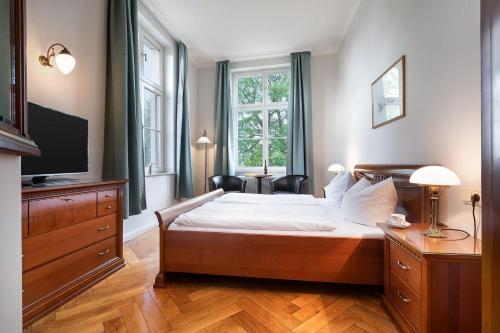 a bedroom with a bed with a television and a dresser at Hotel Prinz Heinrich in Werder