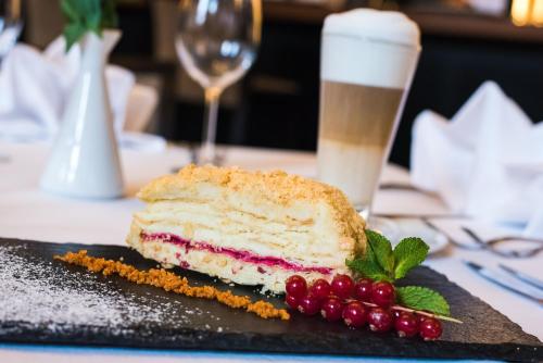 a piece of cake on a black plate with berries at VICTORIA Hotel Kaunas in Kaunas