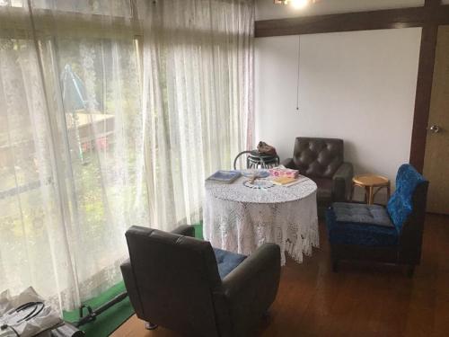 salon ze stołem, krzesłami i zasłonami w obiekcie Ohanabatake w mieście Tsuruoka