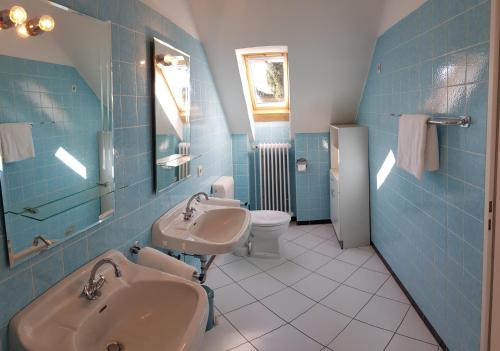 a blue tiled bathroom with two sinks and a toilet at Ferienhaus Anja Bad Pyrmont in Bad Pyrmont