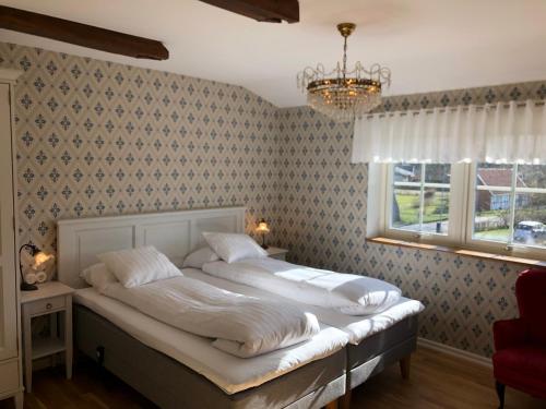 1 dormitorio con cama, ventana y lámpara de araña en Kastanjelund en Yngsjö