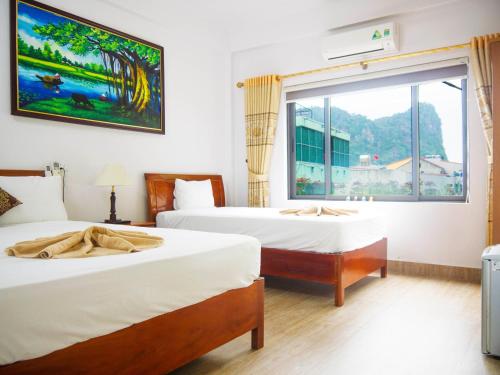 two beds in a room with a window at Thao Nguyen Homestay in Phong Nha
