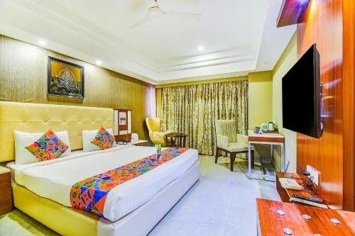 a bedroom with a bed and a desk and a television at The Hotel Orient Taibah in Nagpur