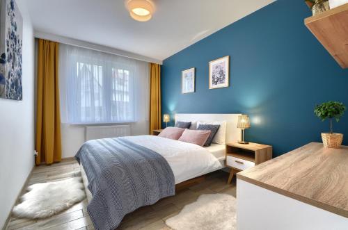 a bedroom with a bed and a blue wall at Mountain Szczyrk ApArt Bratków 10A in Szczyrk