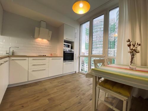 cocina con armarios blancos y mesa de comedor en Scandinavian apartment на Марсельской, en Kryzhanivka