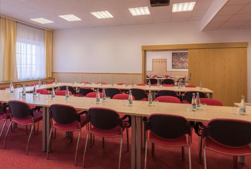 a conference room with a long table and red chairs at Wellness Hotel IRIS in Pavlov